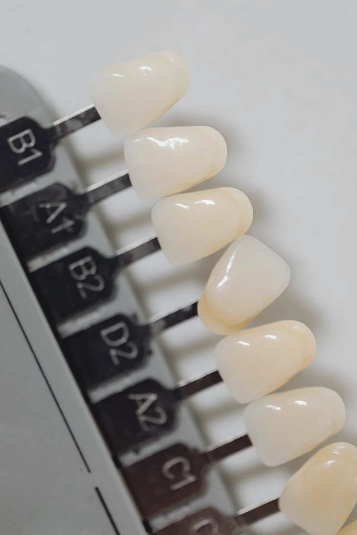 Ceramic dental restorations arranged beside a natural tooth shade guide
