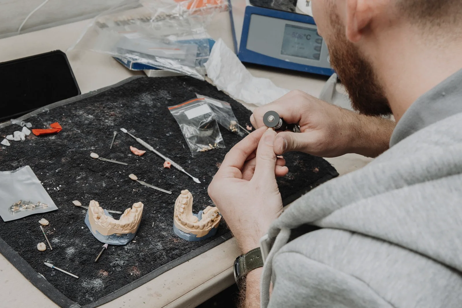 Dental technician shaping a restoration by hand at a laboratory workbench